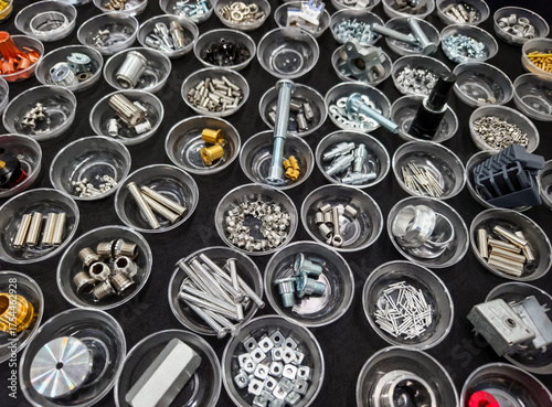 Variety of mechanical components organized in clear containers on a black surface for easy identification and access