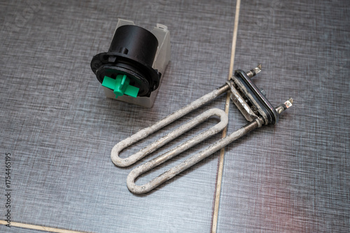 Heating element and pump motor from a washing machine placed on tiled floor after removal