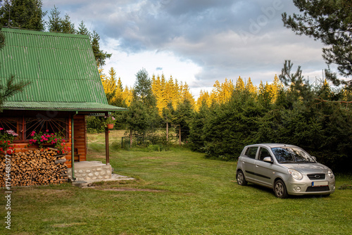 Wooden cabin and car in peaceful forest 