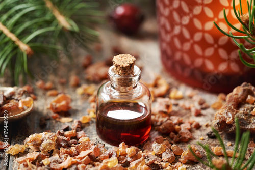Myrrh essential oil and resin with spruce tree branches and candle at Christmas