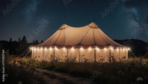 Illuminated large tent in a field at night under a starry sky with soft lighting