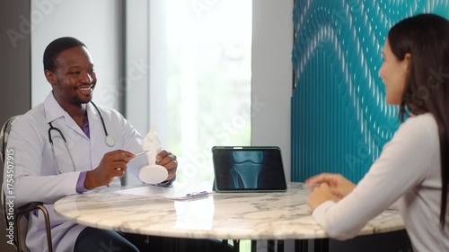 Cheerful doctor and young woman discuss her X-ray results on a tablet computer. A man analyzes an MRI image to make a diagnosis for a patient, Young woman consulting trauma surgeon