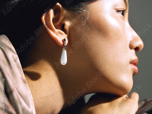 Elegant woman in a soft pink top with statement earrings, captured in a modern setting.
