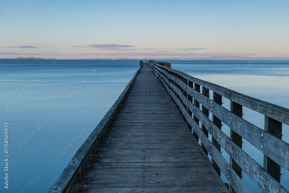 Obraz premium ニュージーランド オークランドの郊外にあるコーンウォリス・ビーチの夕暮れ時の桟橋の上からの風景