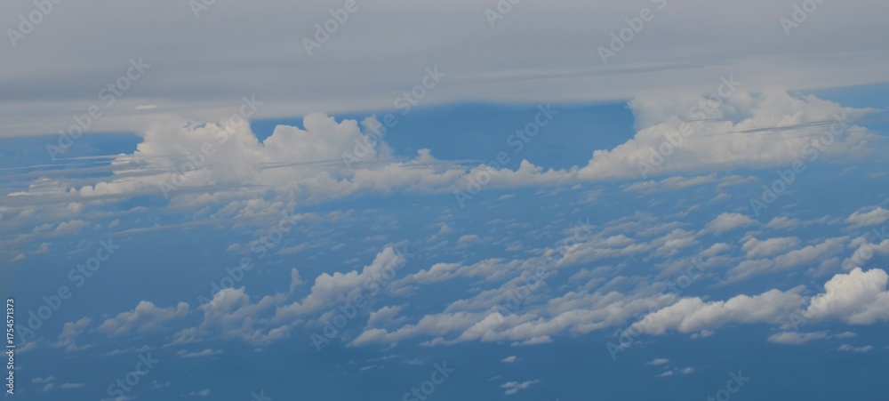 Fototapeta premium Aerial view of scattered cumulus clouds over a deep blue expanse, indicating flight altitude.