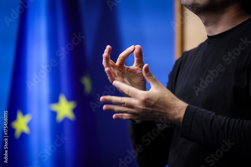 Deaf mute person gestures during a press conference with European Union flag in background
