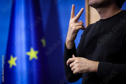Deaf mute person gestures during a press conference with European Union flag in background