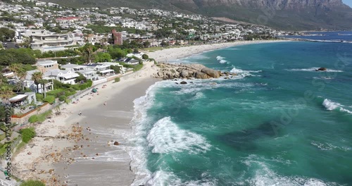 Aerial tilt up shot of Camps Bay beach on a sunny day in Cape Town, Western Cape, South Africa.
