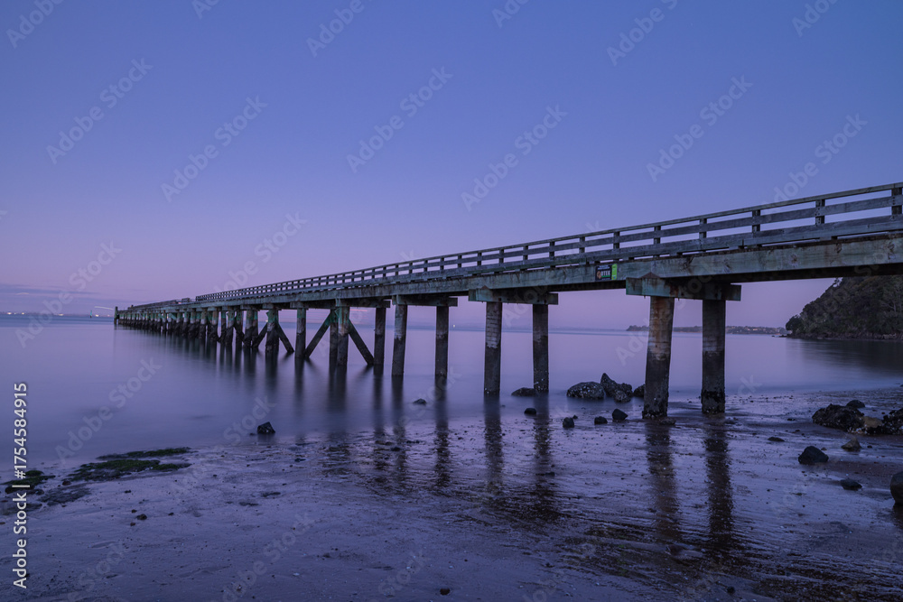 Fototapeta premium ニュージーランド オークランドの郊外にあるコーンウォリス・ビーチの桟橋の風景と黄昏時の空