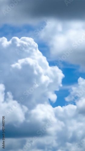 Fluffy white cumulus clouds float in a vibrant blue sky with wispy high-altitude formations