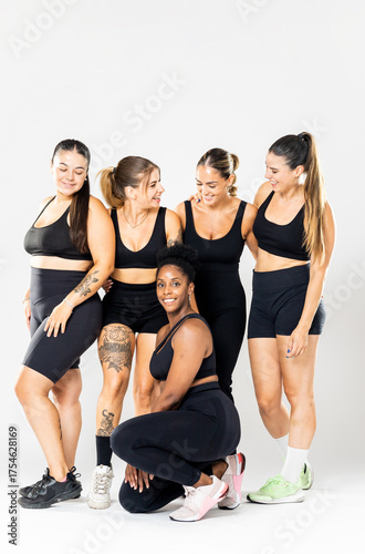 Vertical photo of a group of 5 young women of different ethnicities and body types posing against a white background wearing black sportswear.