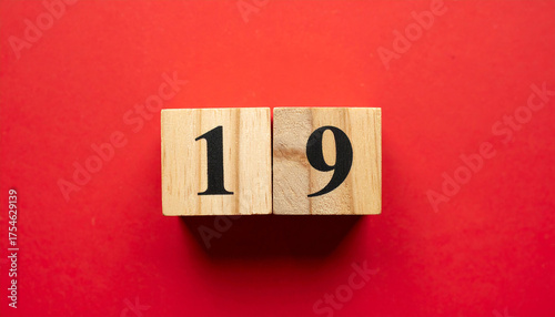 Wooden cubes with number 19 on smooth red background, top view.