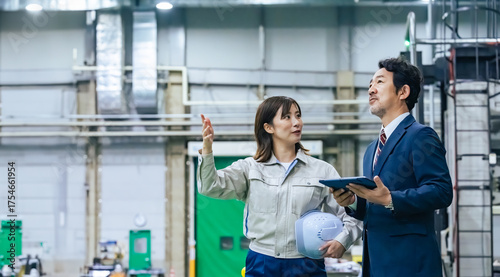 фотографія A male businessman and a female worker inspecting a factory