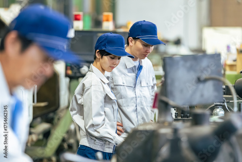 工場で工作機械を操作する作業員グループ