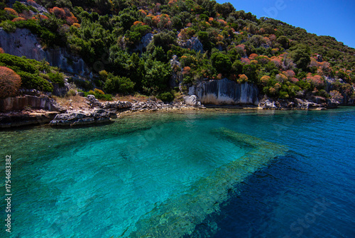 Idyllic Kekova Coastal Scene with Clear Waters, Rocky Cliffs, Historic Lycian Ruins, and Visible Underwater Wall Fragments, Turkey