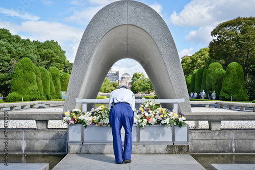 Fotografi A man bows before flowers at Hiroshima Peace Memorial Park