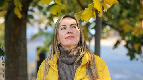 Slavic Woman in Yellow Jacket Looking Up in Autumn Park