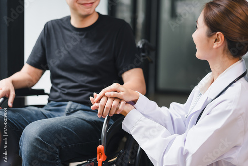 Doctor holding hand of young wheelchair patient in hospital corridor, showing care, support, and reassuring compassion