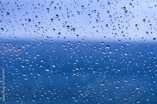 Gotas de lluvia cayendo sobre un cristal con el mar Mediterráneo de fondo, creando una textura natural y atmosférica.