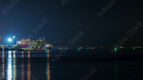 Time-lapse video 4k and motion blur, of a commercial shipping port at twilight, featuring container ships entering and exiting to transport international cargo.