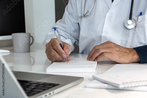 Healthcare professional in lab coat diligently working on a laptop, with stethoscope nearby, representing modern medical practice