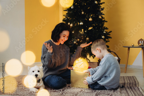 Mother and son opening glowing christmas gift with dog