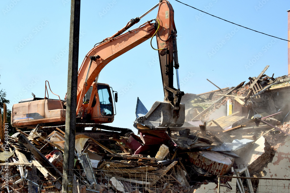 Fototapeta premium A modern excavator clears the rubble of a collapsed building.