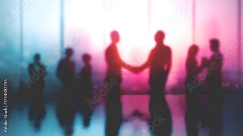 Abstract silhouettes of a business team shaking hands in a modern office with vibrant colorful lighting