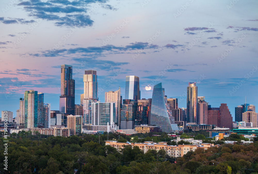 Obraz premium Aerial drone view of the Austin Texas skyline as the full harvest moon is seen rising by the office buildings. Zilker Park in the foreground.