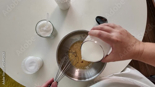 The woman adds ingredients to the beaten eggs for cooking the dish