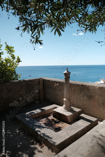 Panoramic view of the Amalfi coast, with a drinking fountain in the foreground.