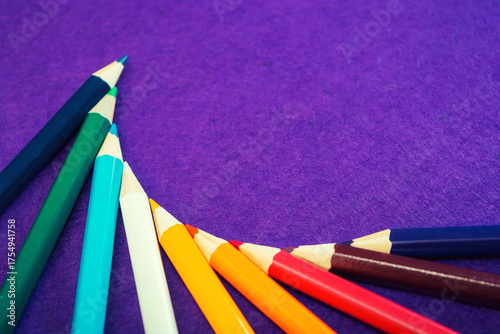 Nine multicolored pencils on a purple felt background. Different colored pencils with space for text. Back to school. Art lessons.