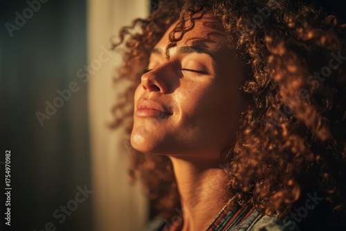 Woman basking in sunlight with eyes closed. Her face turned upwards, she enjoys a moment of peace and tranquility in the golden hour.