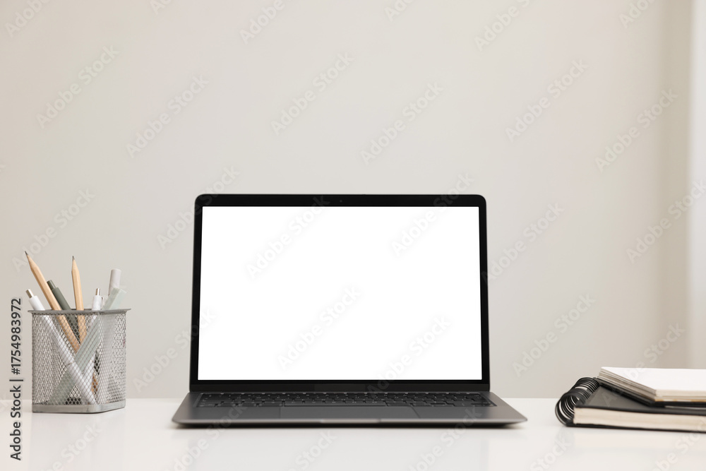 Fototapeta premium Laptop, notebook and stationery on white desk indoors. Mockup for design