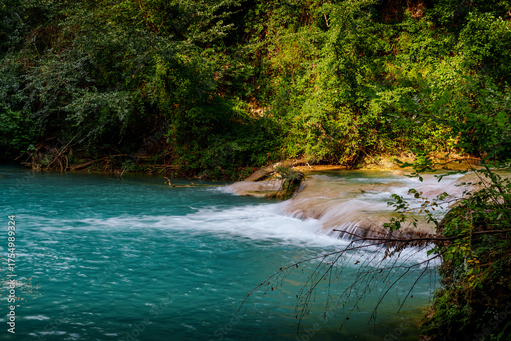 Obraz premium Turquoise mountain river waterfall in lush summer forest, vibrant scenic nature