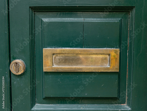 Close-up of a metal lock on a green wooden door, vintage detail and rustic texture background.