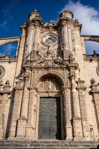 Baroque main entrance of Jerez Cathedral in Cadiz, Spain, showing ornate stone carvings and sculptures under a bright blue sky