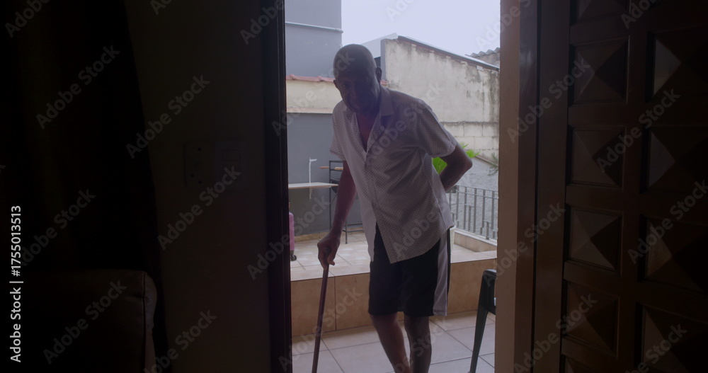 Fototapeta premium Elderly man entering the porch with a cane, capturing a moment of independence, effort, and connection to the outdoors in a tranquil home setting