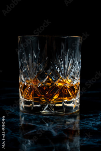 Lowball whisky glass in dark studio environment on dark marble table