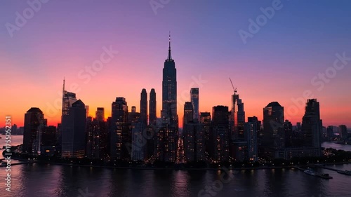 City skyline silhouette at sunset with buildings reflecting in water