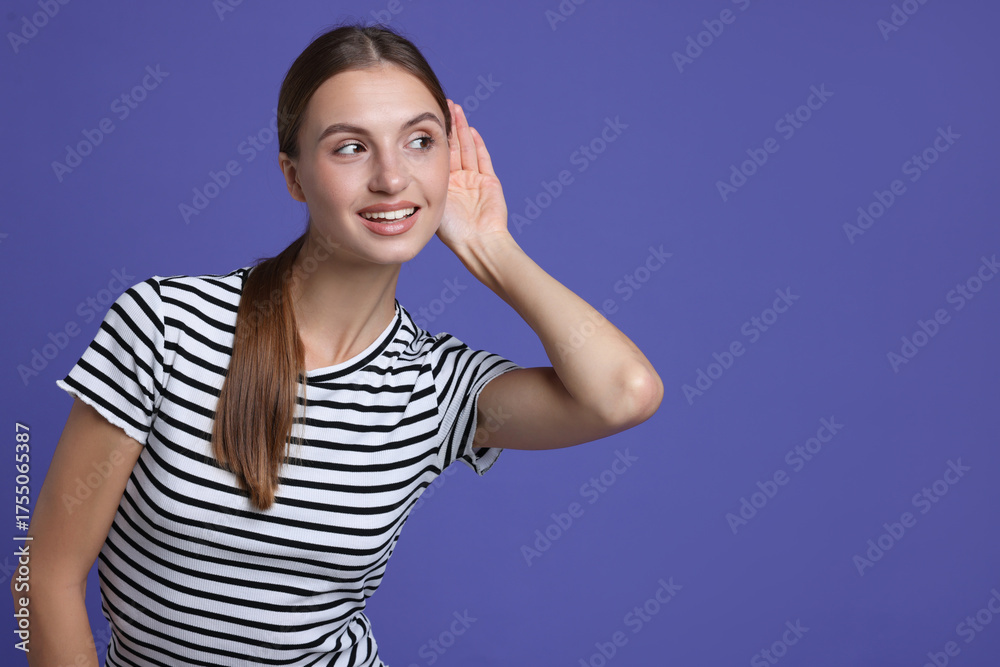 Fototapeta premium Woman showing hand to ear gesture on purple background, space for text