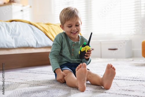Foto Little boy playing with walkie talkie toy at home