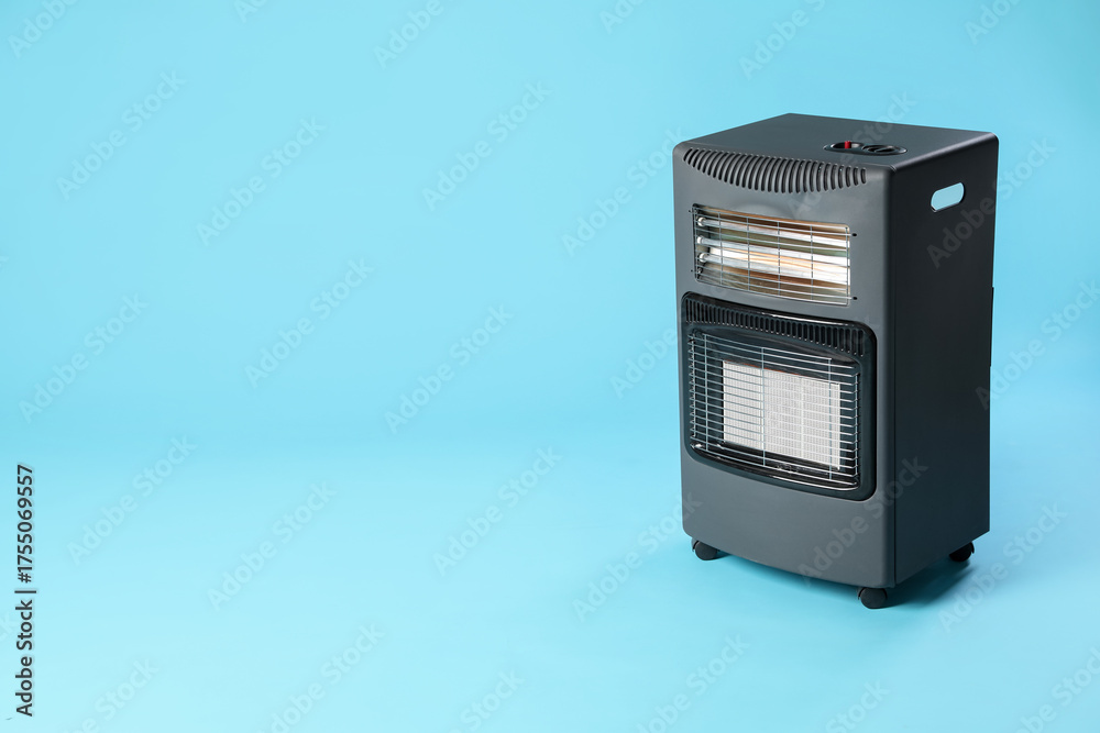 Fototapeta premium Electric heater on light blue background. Space for text