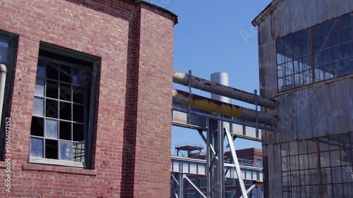 Abandoned Industrial Brick Building with Metal Pipes Under Blue Sky