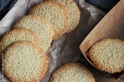 Sesame cookies lie on paper on a wooden table