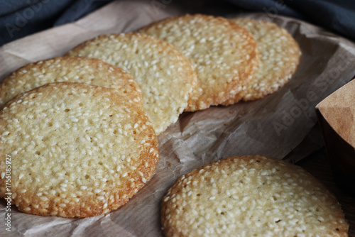 Sesame cookies lie on paper on a wooden table