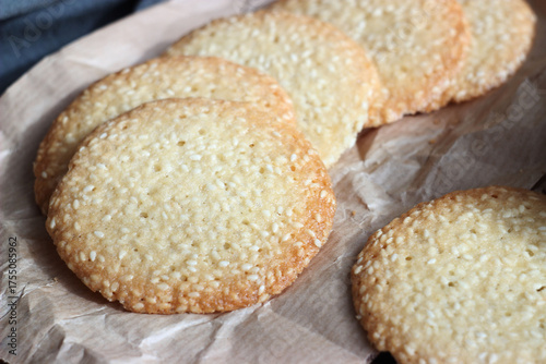 Sesame cookies lie on paper on a wooden table