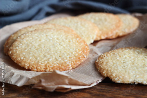 Sesame cookies lie on paper on a wooden table
