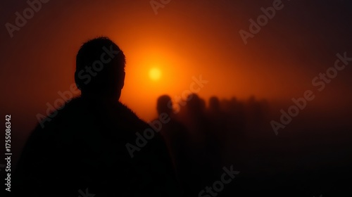 Silhouetted crowd walking into orange haze at sunset