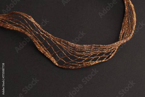Gold, bronze metallic copper braided wave wire on gray black. Abstract light, shadow texture background.